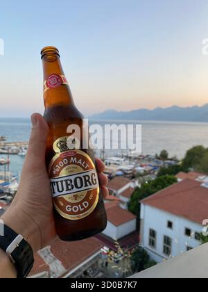 17 giugno 2025, Antalya, Turchia. Sorseggiando una birra Tuborg Gold fredda mentre si affaccia sul porticciolo e il sole tramonta ad Antalya, creando un'atmosfera rilassante Foto Stock