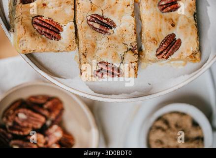 Un piatto di tre barrette di burro di arachidi si trova su un piatto bianco. Accanto al piatto si trova una ciotola di arachidi Foto Stock