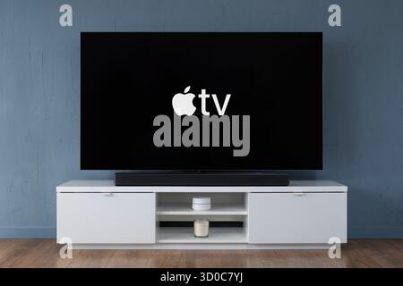 Il logo del servizio di streaming Apple TV è visibile su un moderno televisore OLED widescreen. Foto Stock
