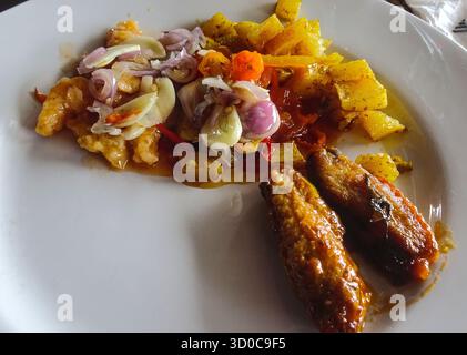 Piatto di piatti assortiti a buffet, tra cui ali di pollo, patate e aglio, con una varietà di piatti salati preparati al momento. Foto Stock