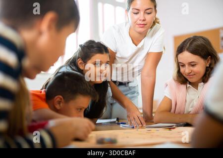 Schoolkids con insegnante che gioca a un tavolo educativo in classe Foto Stock