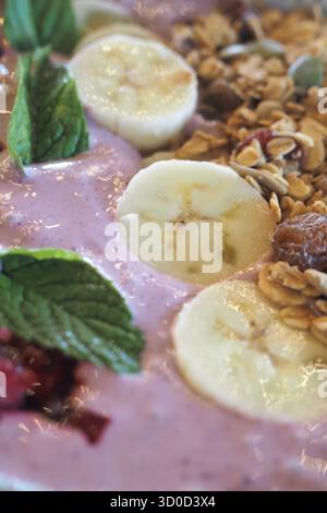 Recipiente per frullati fresco con condimenti di banana e muesli Foto Stock