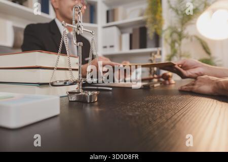 Un avvocato professionista che discute questioni legali con un cliente in un ufficio, fornisce consulenza legale e servizi di revisione dei documenti, simboleggia la giustizia, t Foto Stock