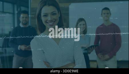 Donna d'affari in piedi che incrocia le braccia e sorride nell'area conferenze, con tablet, schermo e grafici Foto Stock