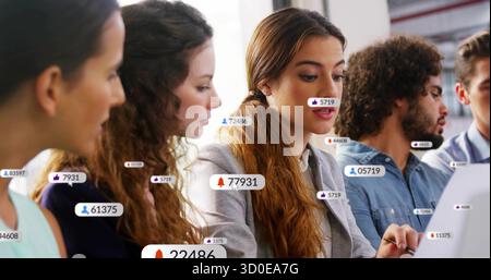 Digita donna in un blazer grigio alla scrivania dell'ufficio, controllando le icone di notifica sul notebook Foto Stock
