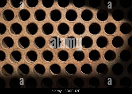 Piastra tubolare dello scambiatore di calore o della texture macro di primo piano della caldaia con sfondo industriale ombra con depositi minerali duri insolubili scala dei sali Foto Stock
