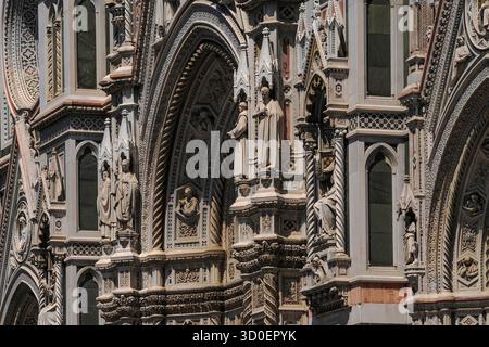 Un tripudio di dettagli decorativi: Statue a grandezza naturale si stagliano sotto tettoie neogotiche o neogotiche con pinnacoli in mezzo a fluting a spirale e marmo toscano intarsiato sulla facciata del Duomo di Firenze del XIX secolo a Firenze, Toscana, Italia. L'architetto Emilio De Fabris armonizzò il suo elaborato disegno con la cattedrale medievale e rinascimentale utilizzando marmo simile: Bianco di Carrara, verde di Prato e rosso di Siena. Foto Stock