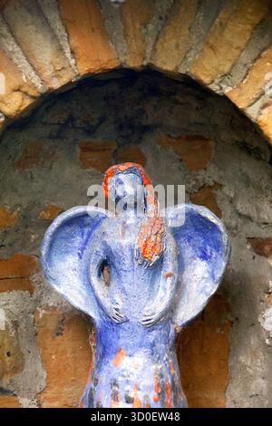 Scultura in pietra intemprata di un angelo in un arco di mattoni Foto Stock