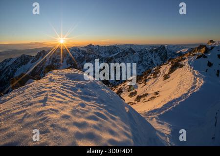 Vista aerea della luce del sole dorata che bacierà la vetta innevata Rysy, gettando lunghe ombre sugli alti Tatra, Tatranska Javorina, High Tatra, Slovacchia. Foto Stock