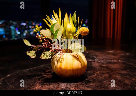 Una vibrante composizione floreale nativa australiana con eucalipto e fiori simili a protea, esposti in un vaso decorativo di notte. Foto Stock