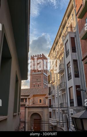 La spettacolare torre mudejar della Chiesa di El Salvador, un sito riconosciuto Patrimonio dell'Umanità, si erge maestosamente con la sua caratteristica struttura in mattoni rossastri Foto Stock