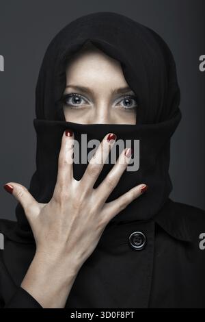 La donna in nero vestito ninja con manicure Foto Stock