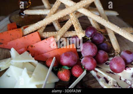 Assortimento di formaggi rustici e tapas su un banco rotondo di legno con una varietà di formaggi fantasiosi, semi-curati bianchi, mirtilli marmorizzati e infusi di spezie Foto Stock