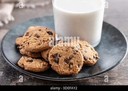 Biscotti con scaglie di cioccolato e latte per colazione su un tavolo di legno Foto Stock