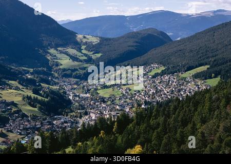 Vista aerea di una città di valle incastonata tra lussureggianti montagne verdi sotto un cielo luminoso, Ortisei, Trentino-alto Adige/Südtirol, Italia. Foto Stock