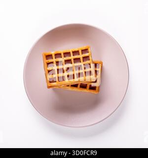 Appetitosi waffle belgi serviti su un piatto di ceramica crema, con una deliziosa vista dall'alto che mostra la loro consistenza dorata e la soffice Foto Stock