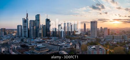 Vista aerea di grattacieli scintillanti che piangono il cielo crepuscolo, proiettando lunghe ombre sulle vivaci strade della città, Francoforte sul meno, Assia, Germania. Foto Stock
