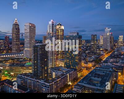 Veduta aerea dei grattacieli che piangono il cielo crepuscolo, le loro finestre illuminate rispecchiano le luci della città sottostante lungo Mainzer Landstraße, Francoforte sul meno, Assia, Germania. Foto Stock
