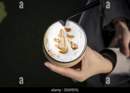 Un bicchiere di caramello di ghiaccio con una semplice latte art. Presa dall'alto verso il basso Foto Stock