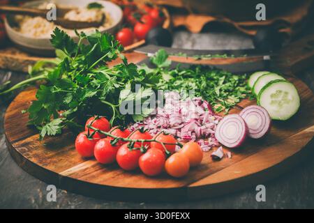 Ingredienti per insalata Tabouleh couscous fatta in casa con verdure fresche ed erbe aromatiche sul tagliere Foto Stock