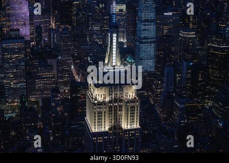 La vista dell'iconico Empire State Building sorge in mezzo a un mare di grattacieli illuminati sotto il cielo notturno scuro, New York, New York, Stati Uniti. Foto Stock