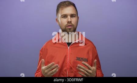 Prigioniero in tuta arancione che mostra il detenuto numero 382586 e gesta a mani aperte in studio; rimorso redenzione. Foto Stock