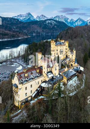 Vista aerea del castello di Hohenschwangau in cima a una collina, con montagne innevate e lago Alpsee sullo sfondo, Schwangau, Bayern, Germania. Foto Stock