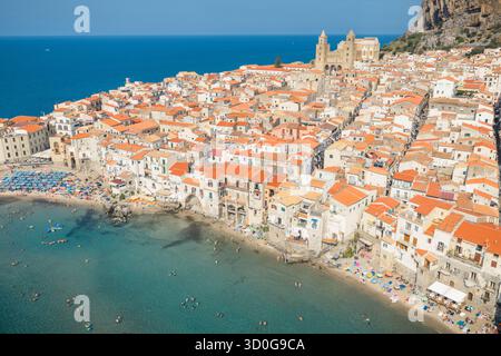 Vista aerea dei tetti in terracotta che scendono fino al mare turchese, coronati dalla maestosa cattedrale di Cefalù, Cefalù, Sicilia, Italia. Foto Stock