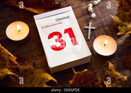 Baviera, Germania - 23 ottobre 2025: FOTOMONTAGGIO, pagina del calendario con data ottobre 31 e l'iscrizione: Giornata della riforma, circondata da candele, croce e foglie autunnali. Immagine simbolica per la festa protestante *** FOTOMONTAGE, Kalenderblatt mit dem Datum 31. Oktober und der Aufschrift: Reformationstag, umgeben von Kerzen, Kreuz und Herbstblättern. Symbolbild für den evangelischen Feiertag Foto Stock