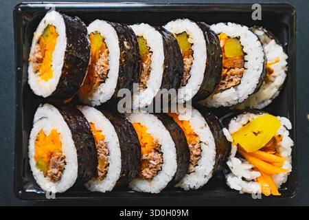 Un vassoio ordinato di involtini kimbap ripieni di riso, manzo, carote e ravanelli sottaceto, avvolti in alghe marine Foto Stock