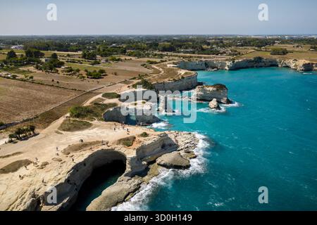 Vista aerea della costa frastagliata dove le bianche scogliere incontrano il mare turchese, un vivido contrasto sotto il sole italiano, Sant'Andrea, Puglia, Italia. Foto Stock