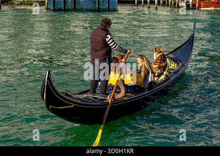 Un gondoliere guida la sua gondola portando un gruppo di donne su un giro in gondola sul Canal grande a Venezia Foto Stock