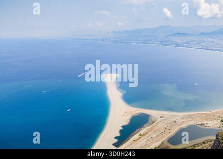 Veduta aerea della spiaggetta di sabbia bianca che incontra il mare blu profondo, in contrasto con lo sfondo di montagne lontane, Marinello, Città metropolitana di Messina, Italia. Foto Stock