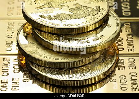 4 diverse monete d'oro da 1 oncia su uno strato di lingotti d'oro Foto Stock