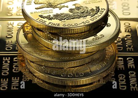 4 diverse monete d'oro da 1 oncia su uno strato di lingotti d'oro Foto Stock