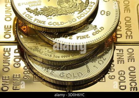 4 diverse monete d'oro da 1 oncia su uno strato di lingotti d'oro Foto Stock