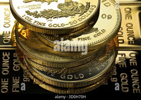 4 diverse monete d'oro da 1 oncia su uno strato di lingotti d'oro Foto Stock