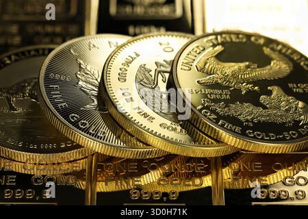 4 diverse monete d'oro da 1 oncia su uno strato di lingotti d'oro Foto Stock