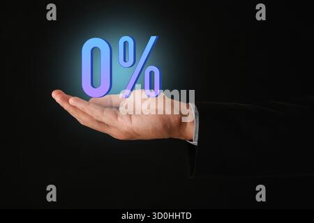 Uomo con in mano un segno dello 0% su sfondo nero, primo piano. Nessuna commissione Foto Stock