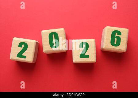 Nuovo anno 2026. Cubi in legno con numeri su sfondo rosso, vista dall'alto Foto Stock
