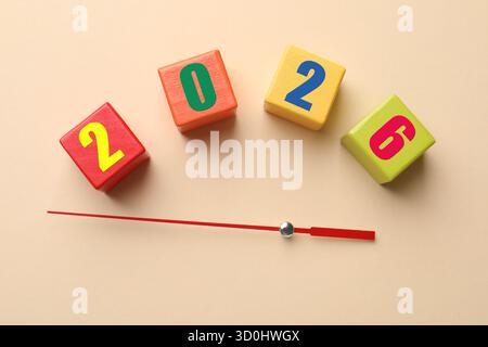 Nuovo anno 2026. Cubi di legno con numeri e frecce su sfondo beige, vista dall'alto Foto Stock
