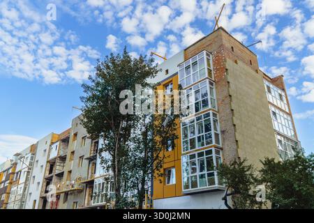 Un edificio residenziale in fase di ristrutturazione e riparazione dopo danni bellici, che mostra un mix di esterni infiniti e nuovi balconi Foto Stock