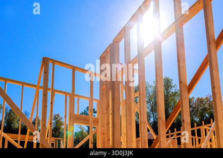 Le travi in legno prendono forma durante l'attività di costruzione di nuove abitazioni in mezzo a un paesaggio sereno. Foto Stock