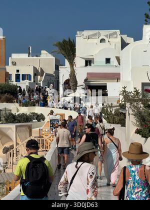 I turisti sulla strada pedonale inondano la splendida città di Oia, una grande destinazione turistica sull'isola di Santorini - Isole Cicladi, Grecia Foto Stock