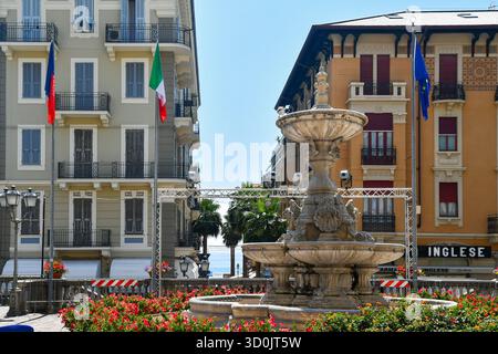 Fontana in pietra in Piazza della Libertà, piazza del municipio, con palme e mare sullo sfondo, in estate, Alassio (Savona), Liguria, Italia Foto Stock