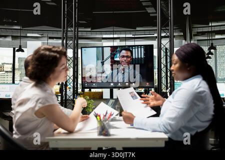 Giovane candidato di colore che chatta con il team di reclutamento durante un colloquio remoto tramite videoconferenza, esplorando esperienze e qualifiche per garantire l'allineamento con i requisiti di posizione. Foto Stock