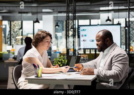 Candidato di sesso nero che firma i documenti e riceve l'approvazione per l'onboarding, entusiasta di una nuova posizione commerciale. Job seeker e recruiter finalizzano il processo di assunzione con questioni legali. Foto Stock