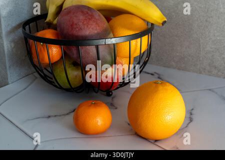 Mela rossa fresca e arancia tagliata a fette su tovagliolo di lino a righe con foglie di quercia autunnale in vaso di ceramica panna sul banco da cucina in marmo. Noce di frutta sana Foto Stock