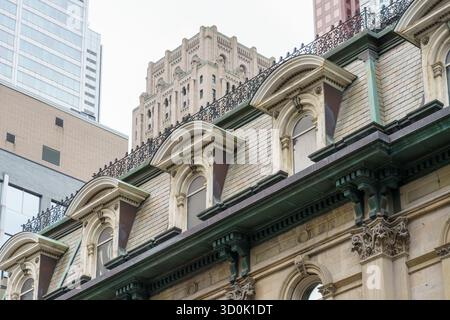 Dettaglio della facciata di un edificio storico con finestre ad arco e finiture ornamentali circondati da moderni grattacieli in centro. Foto Stock