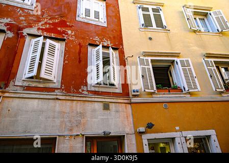 Affacciato su finestre con persiane che si affacciano sulla piazza della città costiera di Muggia, l'unica città portuale d'Italia sul mare Adriatico Foto Stock